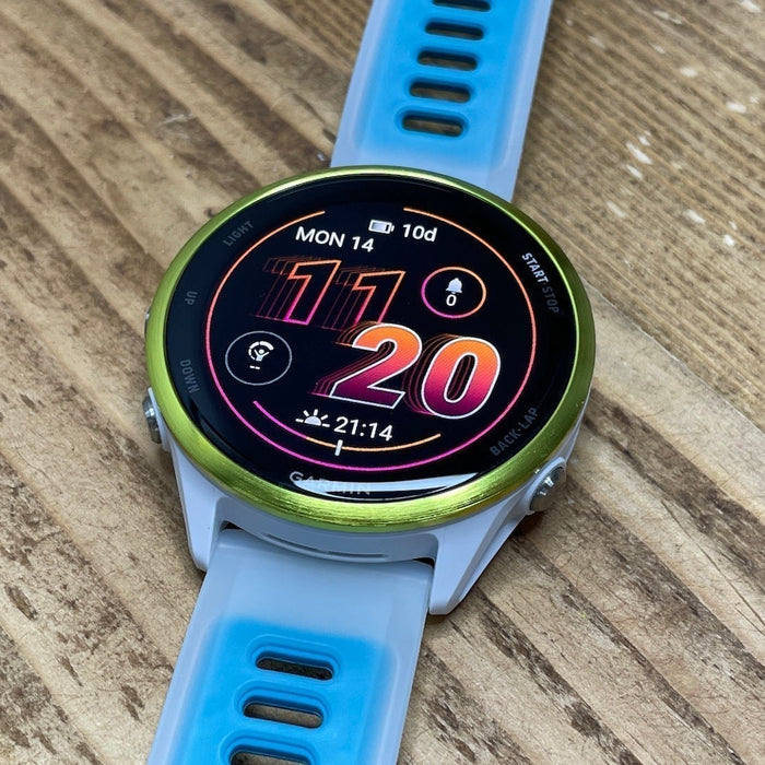 The blue and white Garmin Forerunner 570 laying flat on a woodgrain surface