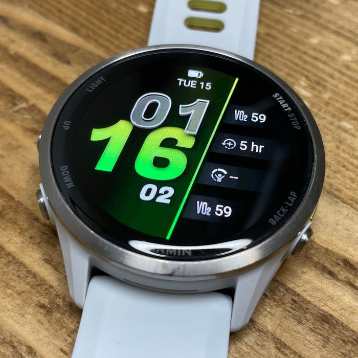 The white Garmin Forerunner 970 running watch laying flat on a woodgrain surface