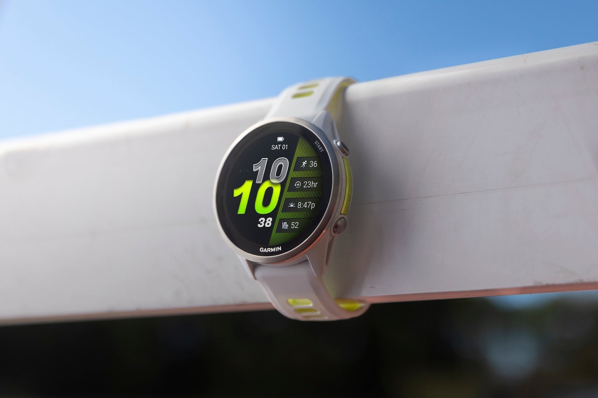 The white Garmin Forerunner 970 running watch around a track hurdle