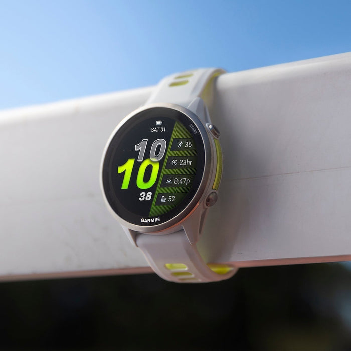The white Garmin Forerunner 970 running watch around a track hurdle