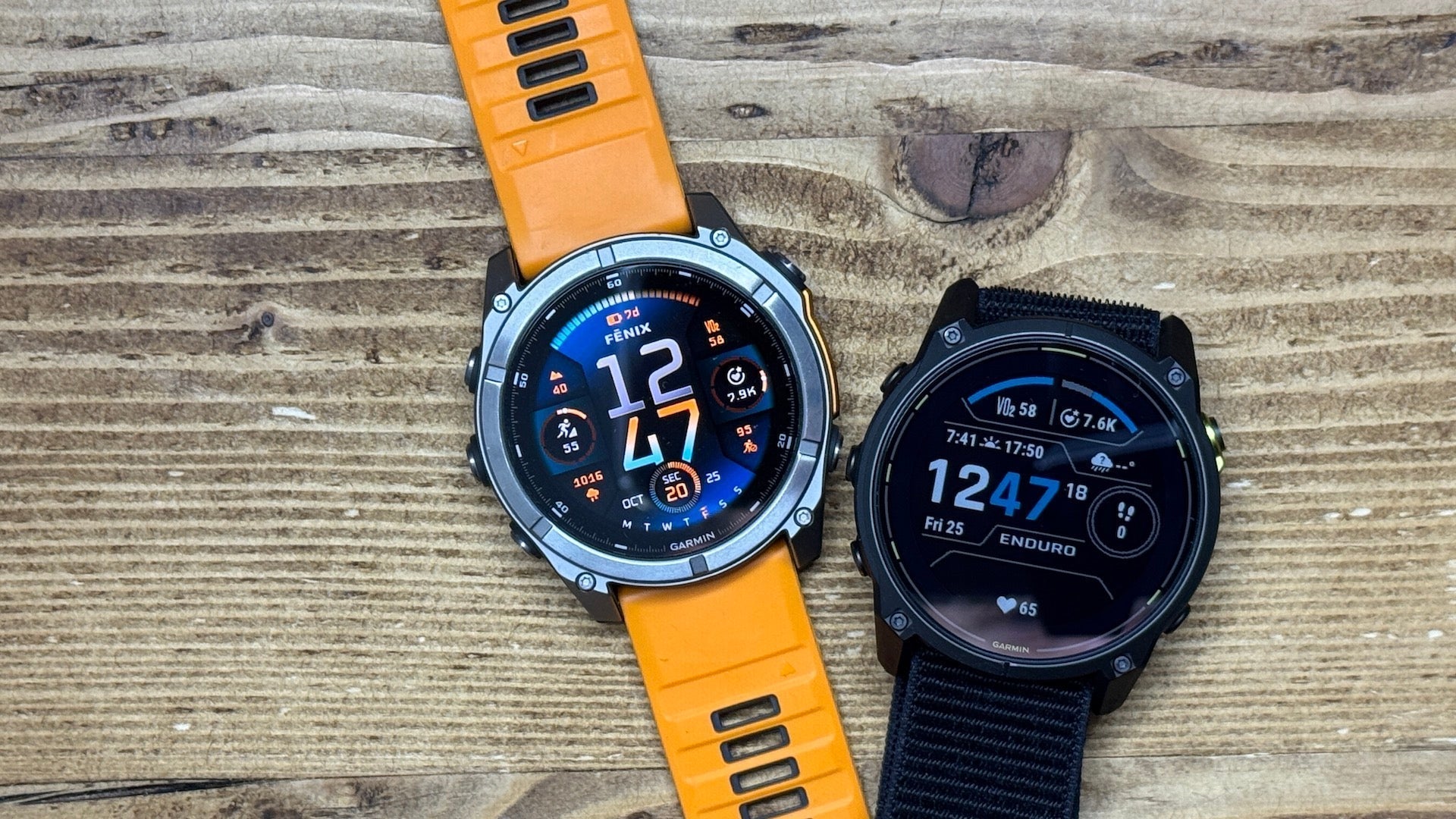 The Garmin fenix 8 and Garmin Enduro 3 watches laying on a wood grain background
