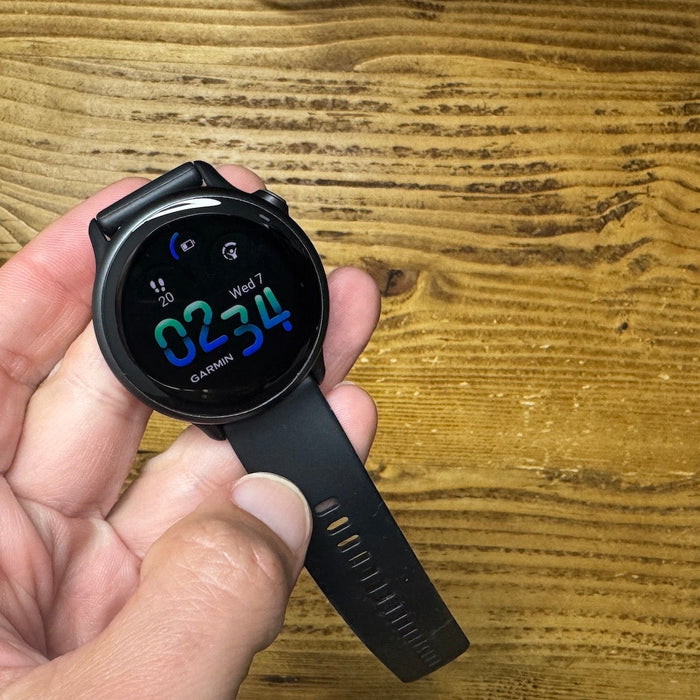 The Garmin vivoactive 6 held in the hand of reviewer and runner Kieran Alger over a wood background