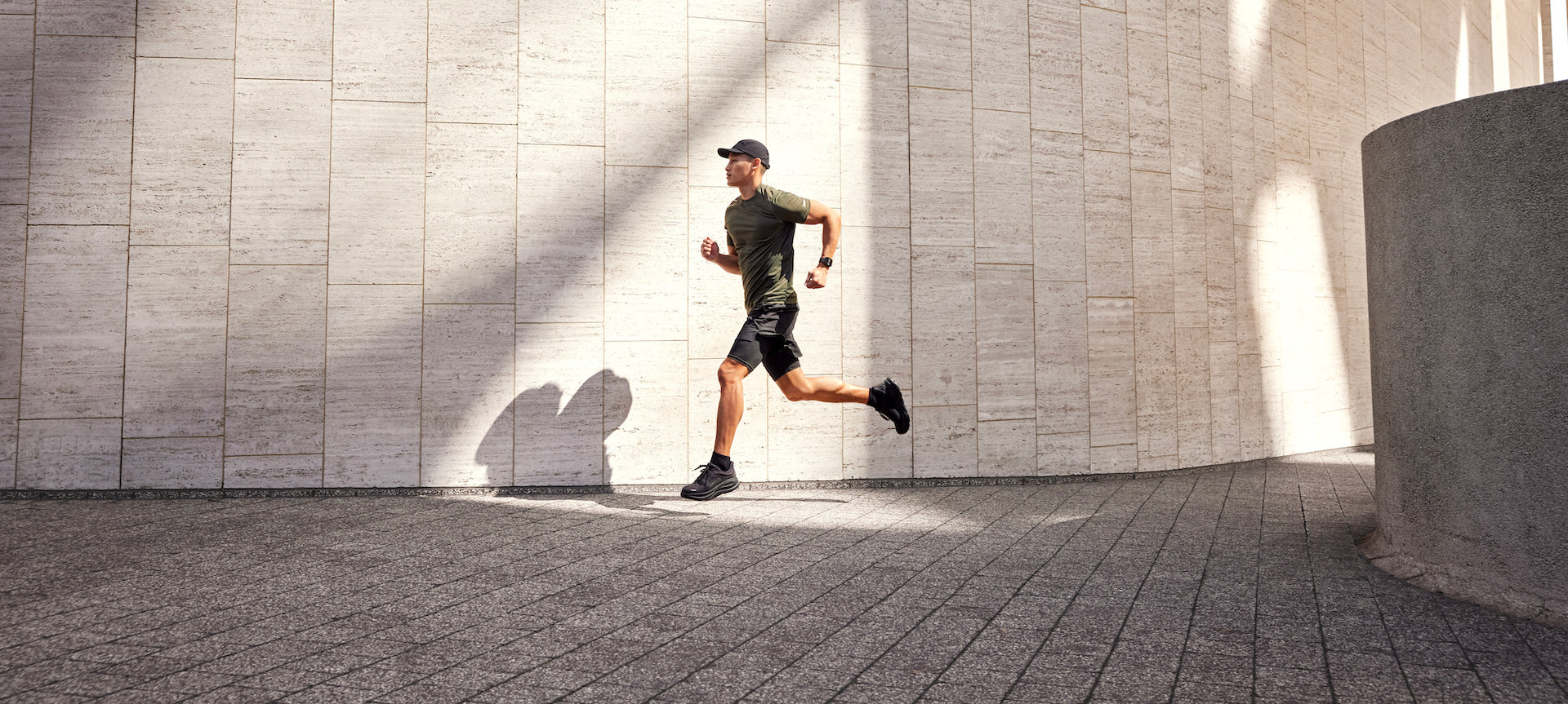 A runner running in a stone plaza with a Garmin Venu X1 GPS smartwatch