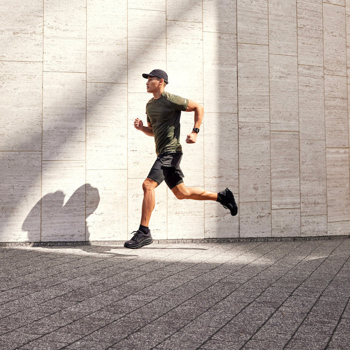 A runner running in a stone plaza with a Garmin Venu X1 GPS smartwatch