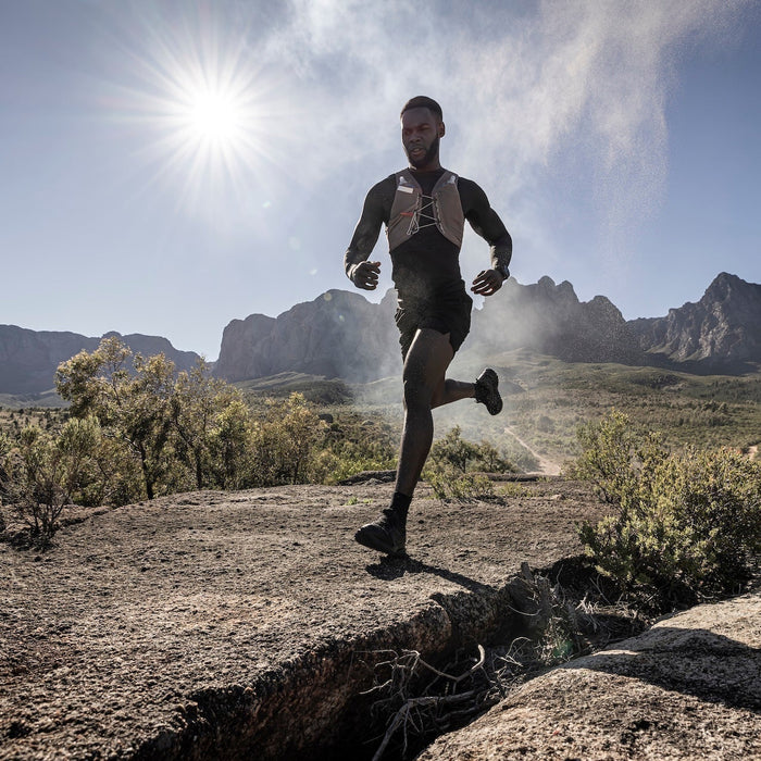 A runner outdoors running in rugged terrain wearing a Garmin fenix 9 Pro