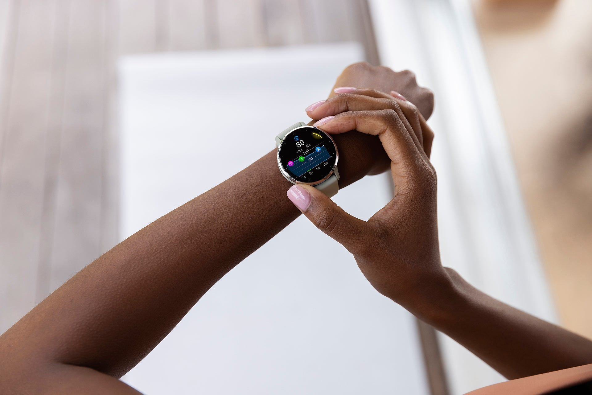 A silver and whitestone Garmin Venu 3 on a female's wrist with one hand adjusting