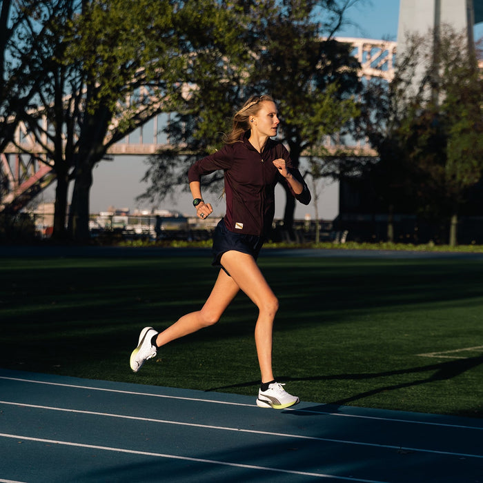 A female runner on a track in the city wearing a Garmin running watch