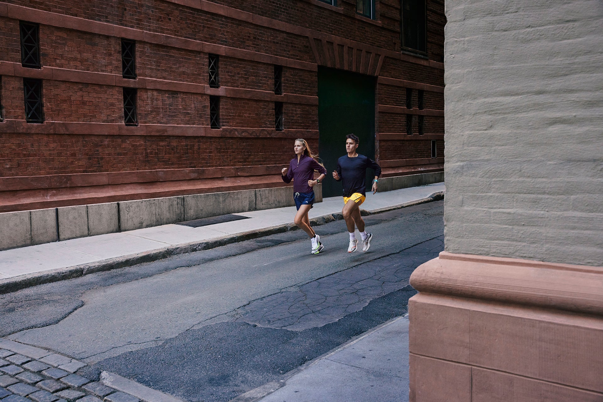 Two runner running out of an alley wearing Garmin Forerunner 265 running GPS watches