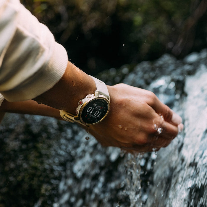 A woman catching water with her hands while wearing the water-resistant Polar Grit X in gold color